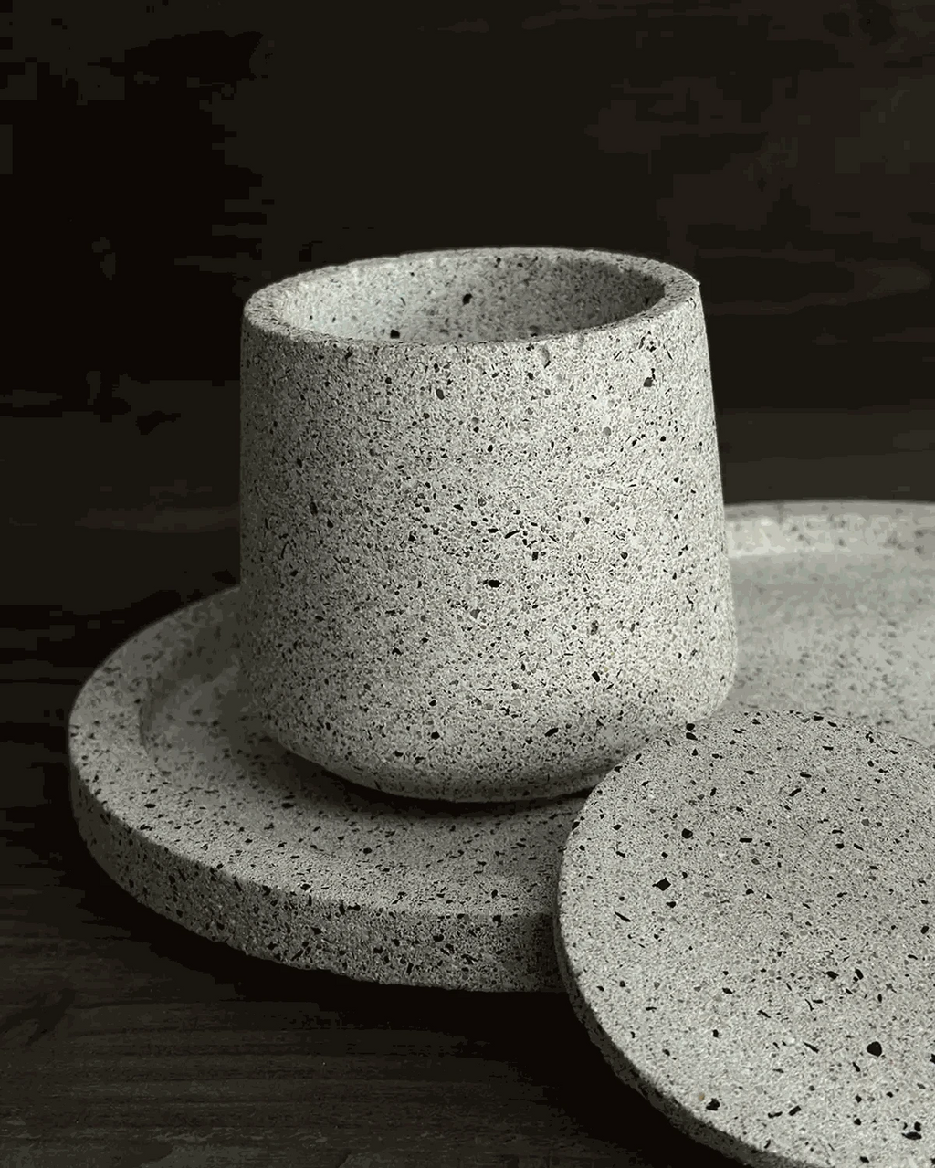 Offene helle Betondose aus Beton auf ovalem Tablett mit losem Deckel