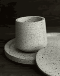 Offene helle Betondose aus Beton auf ovalem Tablett mit losem Deckel