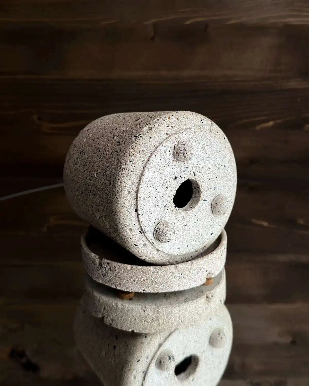 Pflanzgefäß aus hellem Beton mit sichtbarer Unterseite und Ablaufloch auf Untersetzer