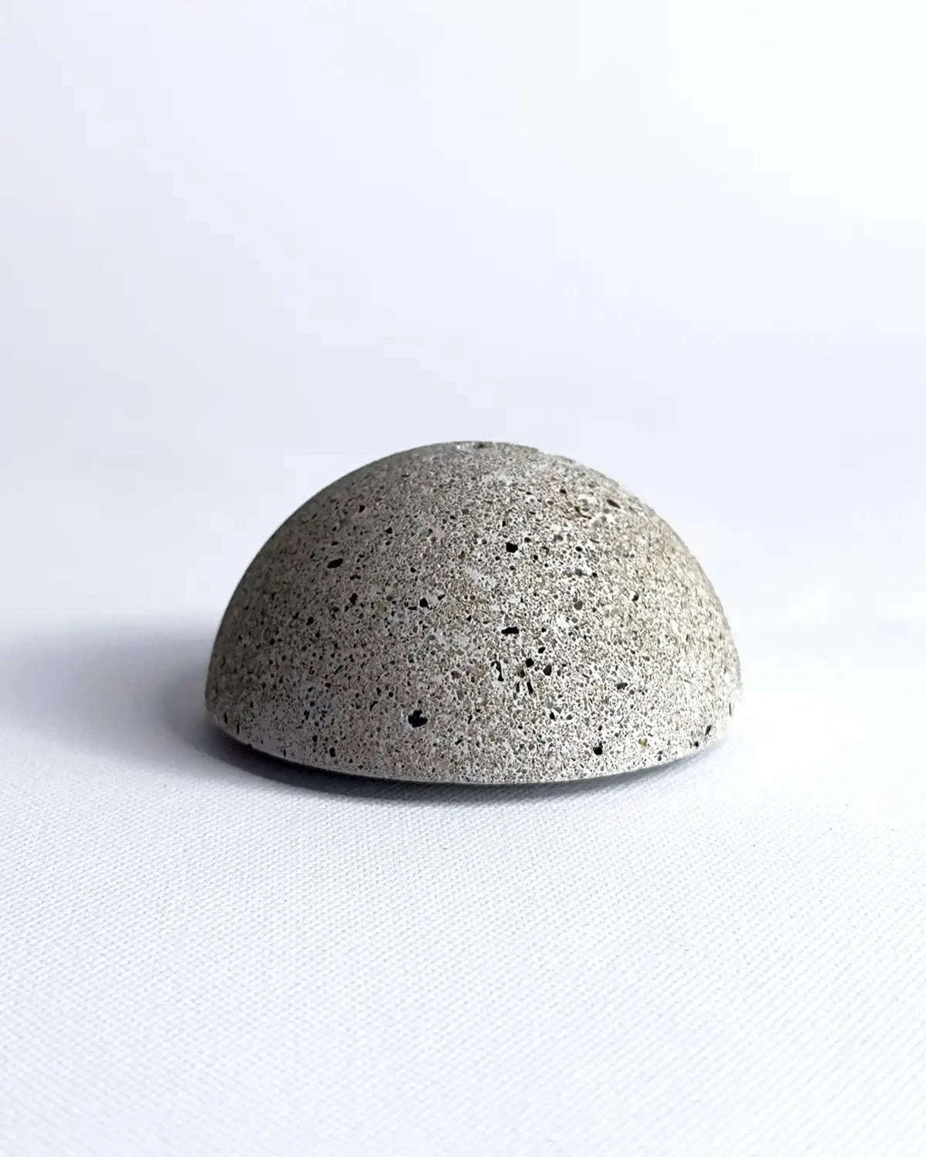 Minimalistischer Räucherhalter aus hellem Beton in halbrunder Form.