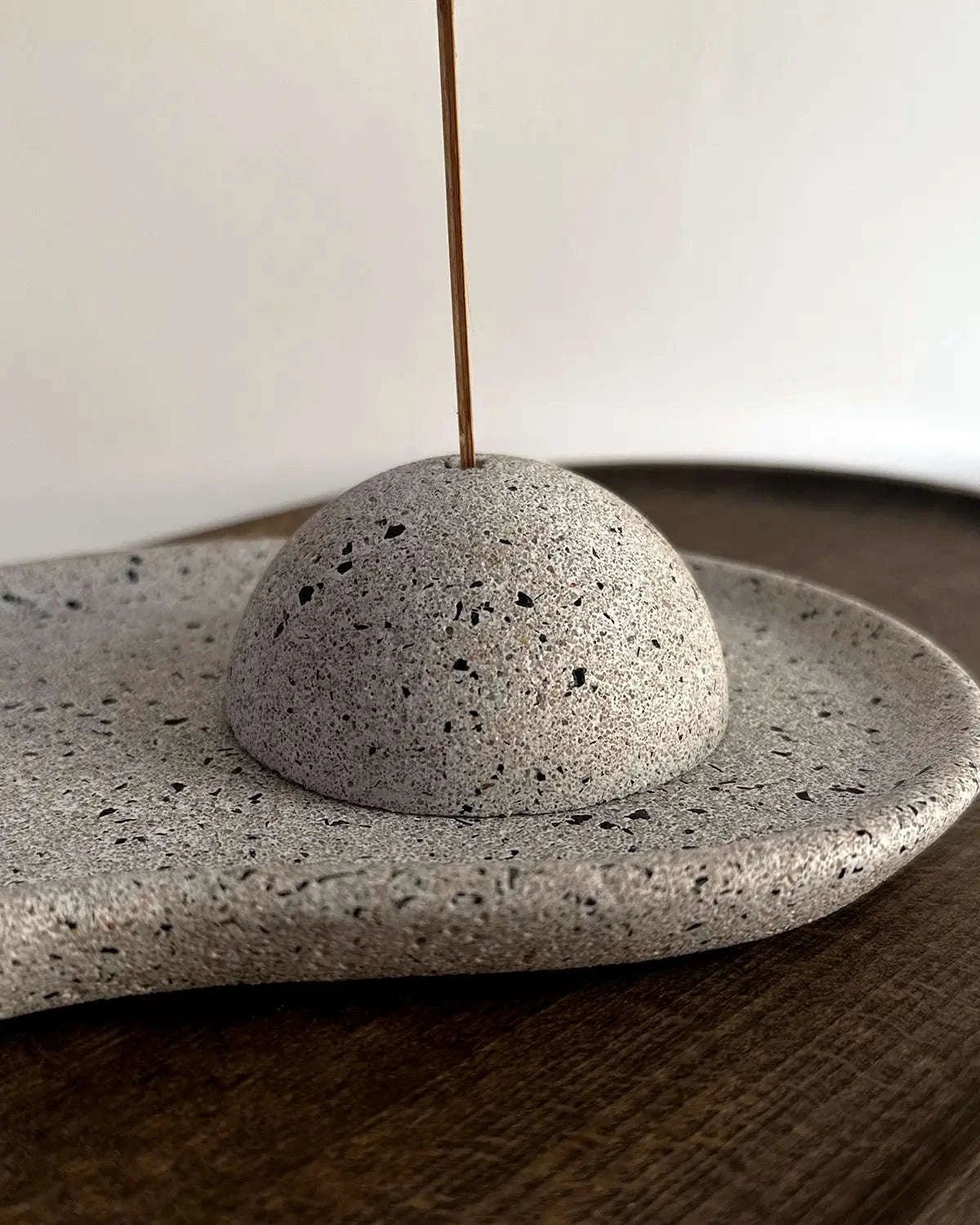 Räucherstabhalter aus Beton auf organischem Dekoteller mit Räucherstäbchen.