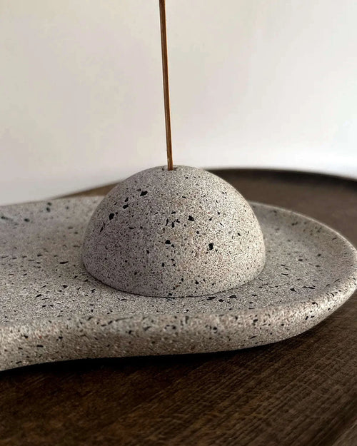 Räucherstabhalter aus Beton auf organischem Dekoteller mit Räucherstäbchen.