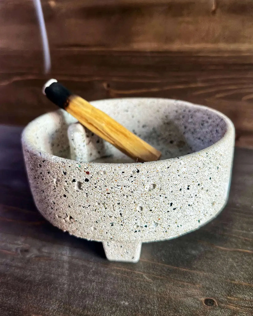 Flache, helle Betonschale Eunoia mit eingelegtem Palo-Santo-Holz auf Untergrund.