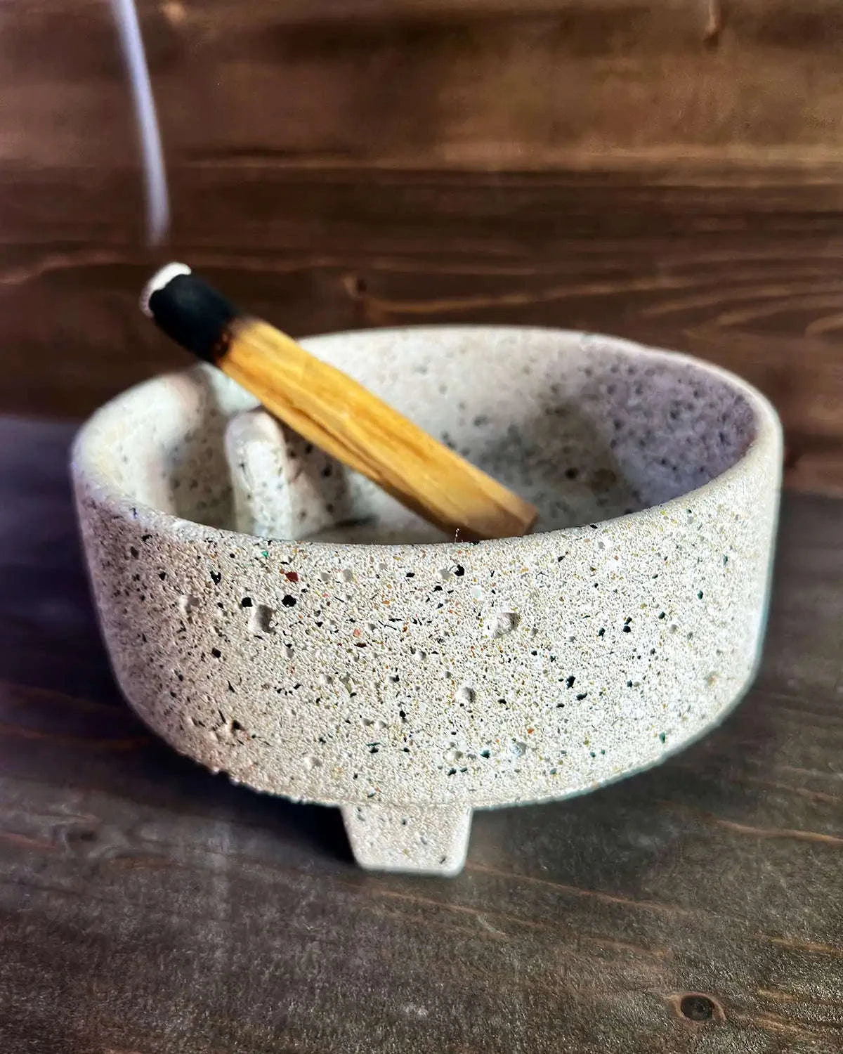 Flache, helle Betonschale Eunoia mit eingelegtem Palo-Santo-Holz auf Untergrund.