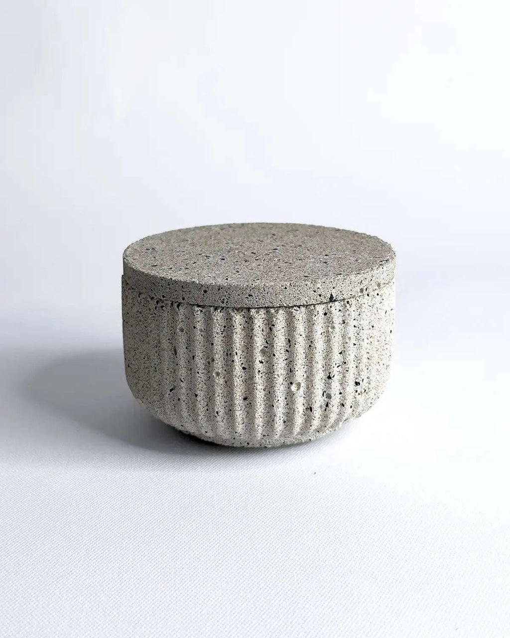 Geriffelte Betonschale mit passendem Deckel in heller Steinoptik.