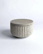 Geriffelte Betonschale mit passendem Deckel in heller Steinoptik.
