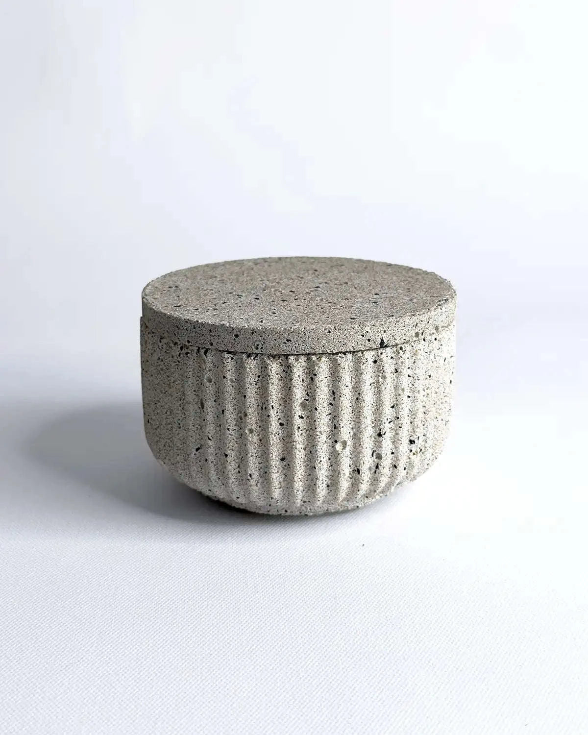 Geriffelte Betonschale mit passendem Deckel in heller Steinoptik.