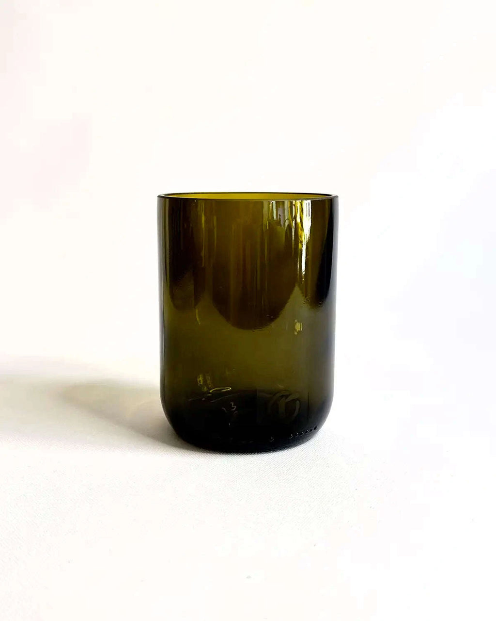 Trinkglas aus antikgrünem Upcycling-Glas vor hellem Hintergrund