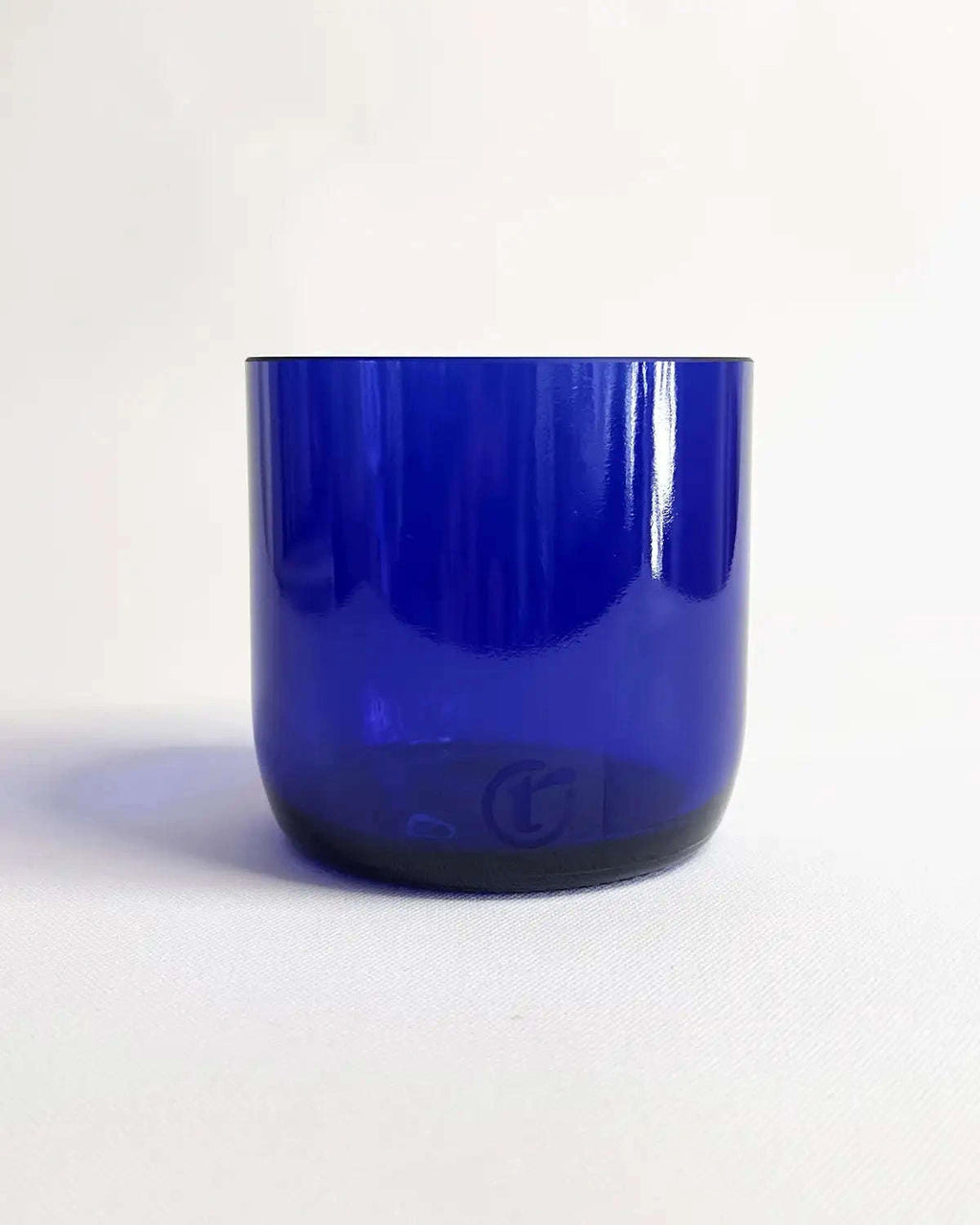 Blaues Trinkglas aus Weinflasche vor hellem Hintergrund