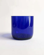 Blaues Trinkglas aus Weinflasche vor hellem Hintergrund