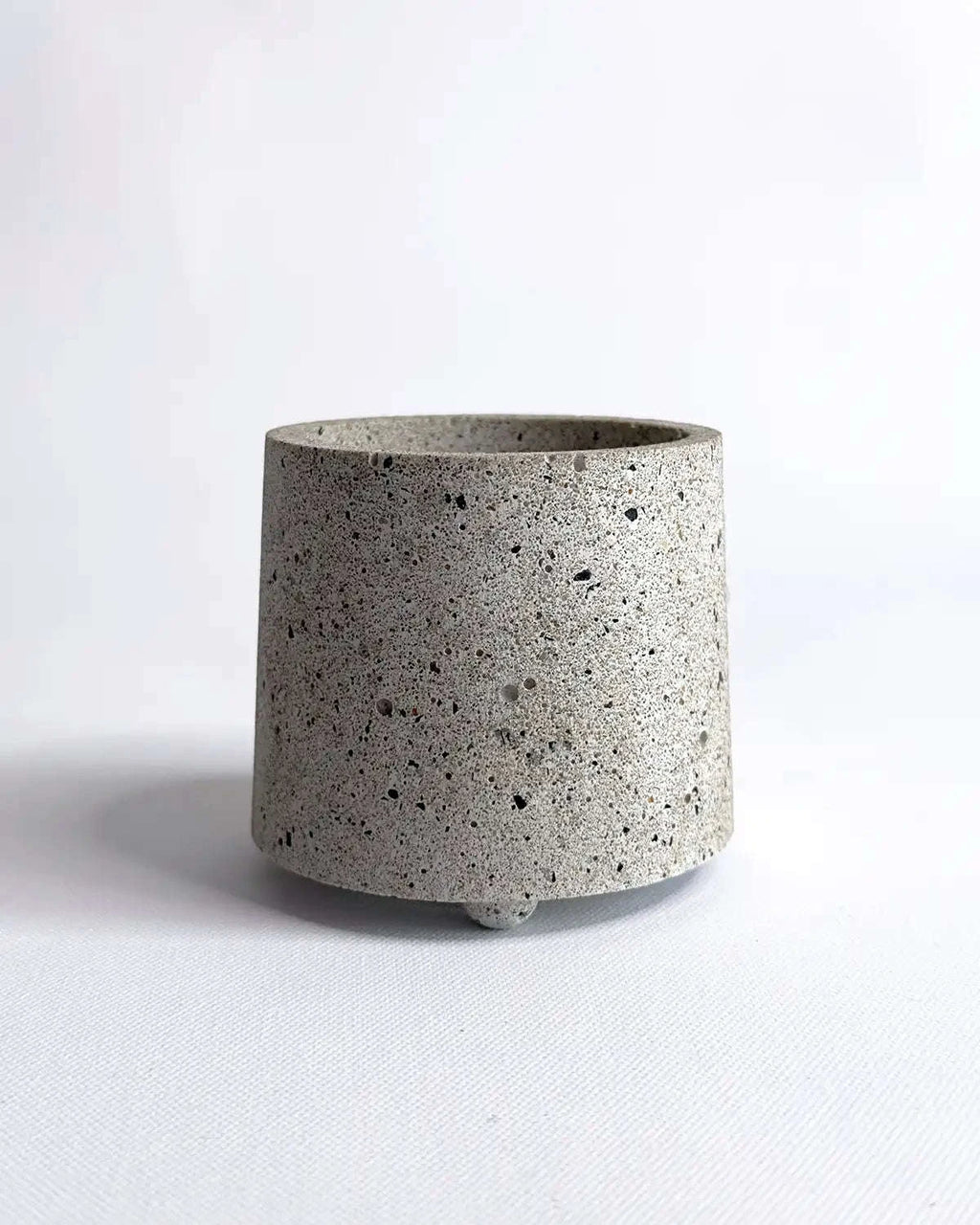 Weißer, zylindrischer Beton-Übertopf Little Potvin mit rauer Oberflächenstruktur.