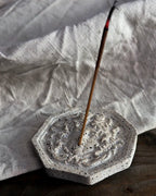 Räucherstäbchenhalter Meduza aus Beton auf ungefärbtem Leinentuch mit Räucherstäbchen.