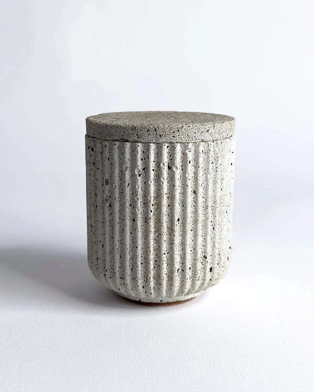 Aufbewahrungsbehälter aus Beton mit passendem Deckel in geriffelter Form.