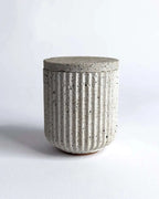 Aufbewahrungsbehälter aus Beton mit passendem Deckel in geriffelter Form.