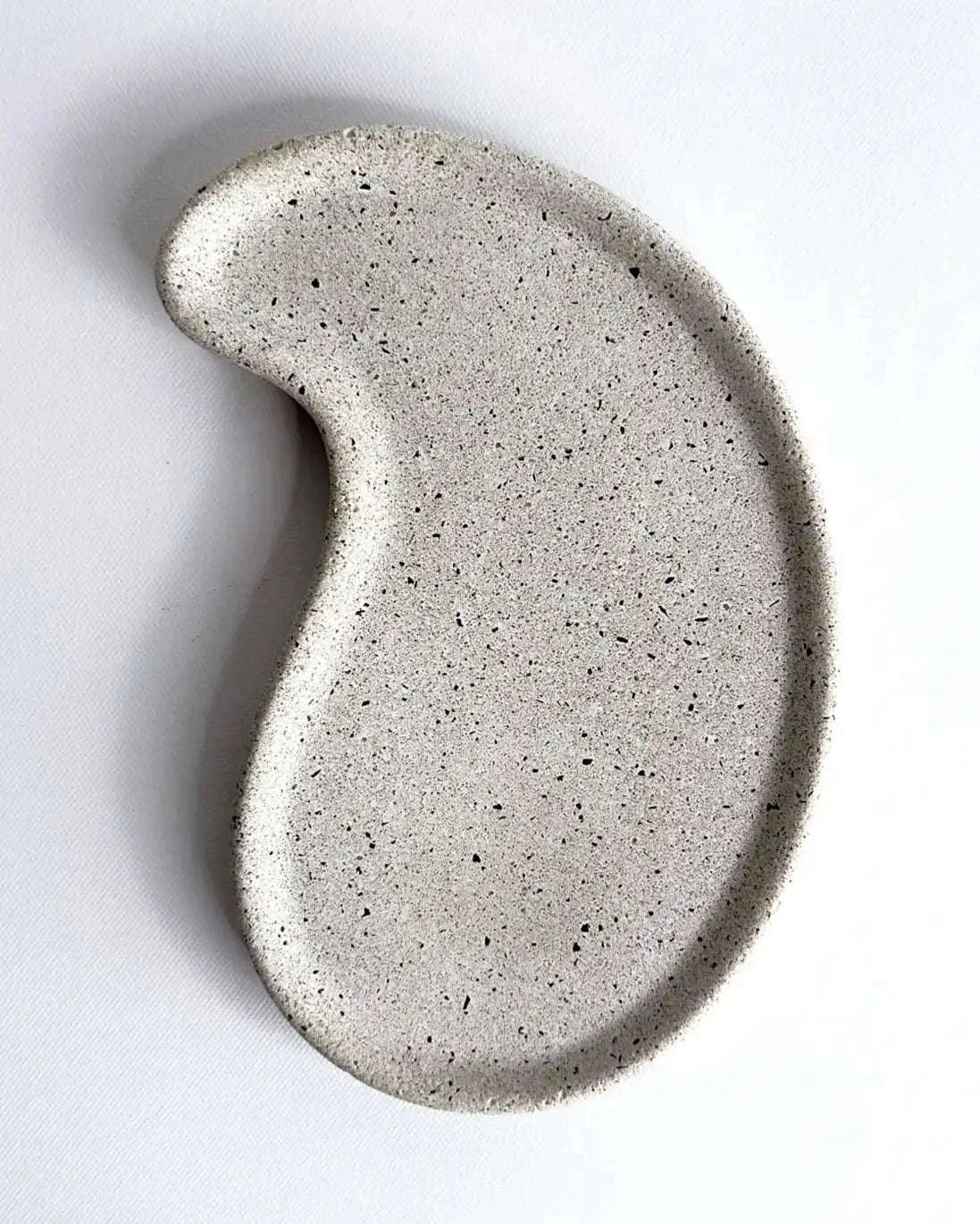 Schwarzes Betontablett in Nierenform aus der Vogelperspektive.