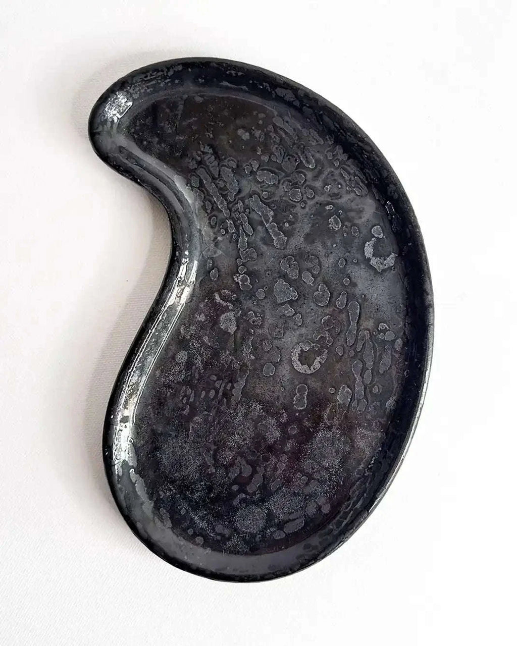 Schwarzes Betontablett in Nierenform aus der Vogelperspektive.