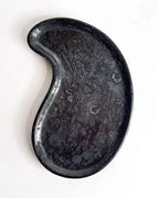 Schwarzes Betontablett in Nierenform aus der Vogelperspektive.