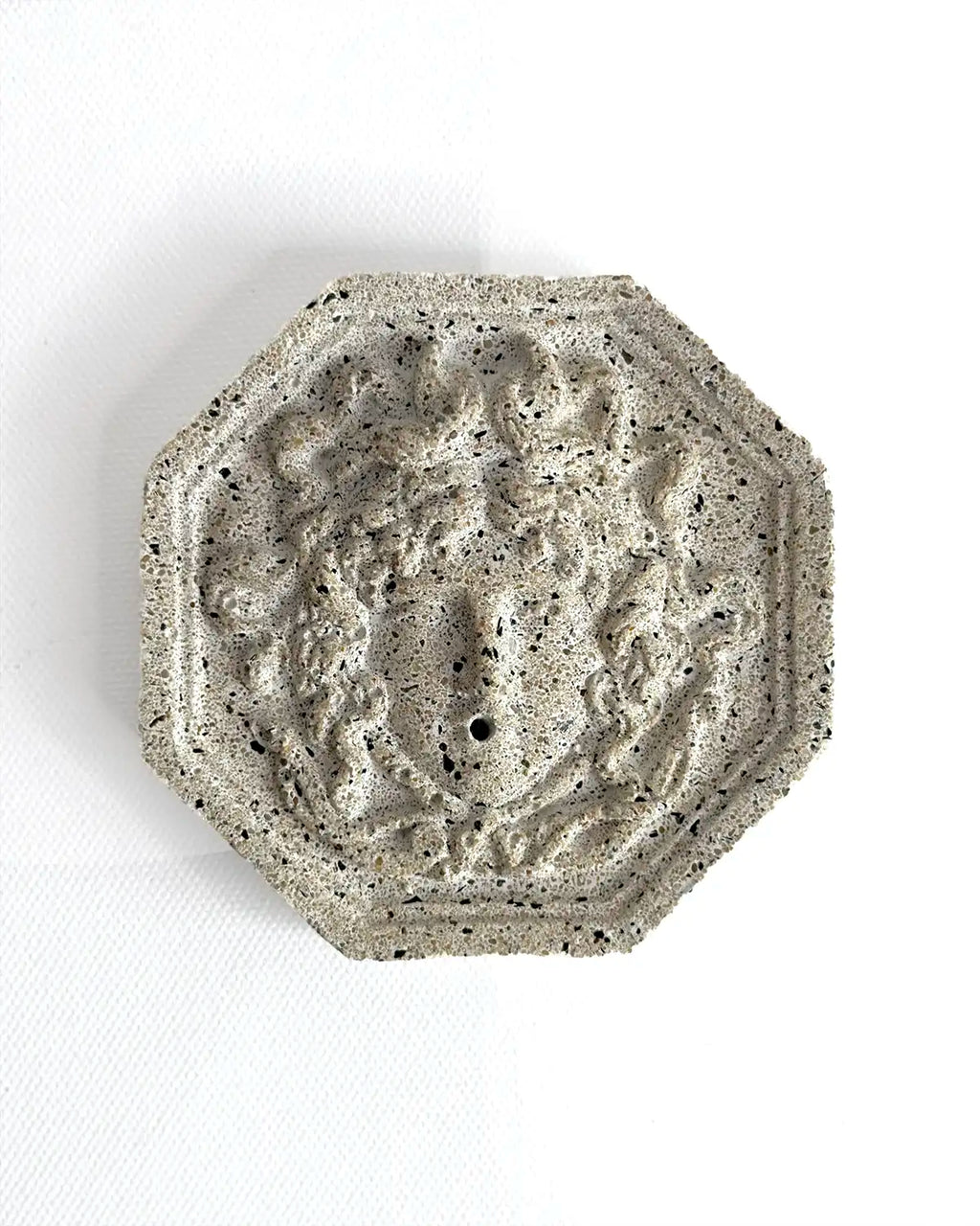 Antik anmutender Räucherstäbchenhalter Meduza aus hellem Feinbeton auf neutralen Untergrund.